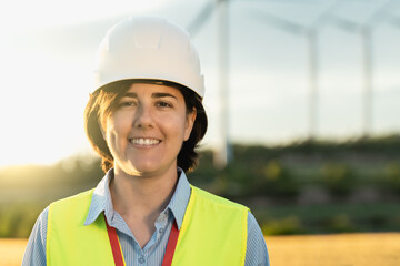 Sustainable energy - Engineer working at solar farm construction with wind mill field on background