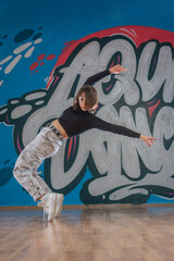 Attractive young woman doing breakdance move over graffiti background