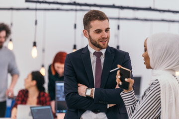 Portrait of a formal businessman and young African American businesswoman posing with their team in a modern startup office. Marketing concept. Multi-ethnic society..