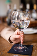 A glass filled with water in hand of a young girl close up