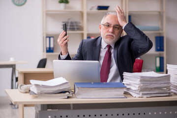 Fototapeta premium Aged male employee and too much work at workplace