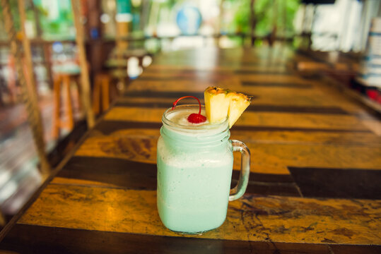 Colorful tropical cocktails on wooden bar. Mixology in pool holiday setting. Caribbean cocktails. Colorful cocktails in caribbean bar hotel.