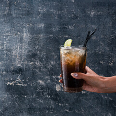 hand of girl holding glass of rum with coke