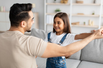 Dad and daughter dancing in living room together