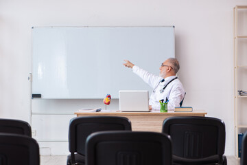 Old male doctor lecturer in the classroom during pandemic