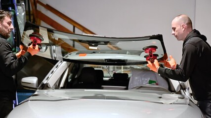 Automobile technician worker replacing windscreen of a car in automobile service station garage. High quality 4k footage