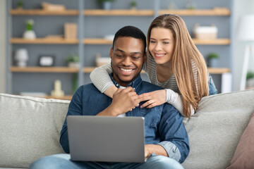 Portrait Of Happy Happy Young Multicultural Spouses Using Laptop At Home