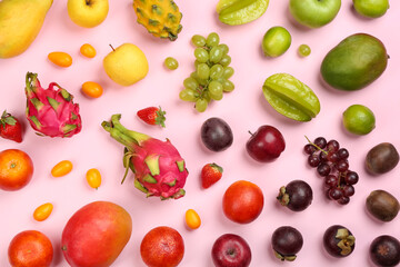 Assortment of fresh exotic fruits on pink background, flat lay