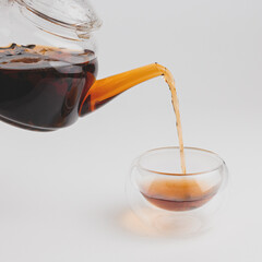 the moment of pouring pu-erh from the teapot into the cup glass