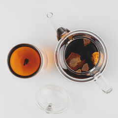 brewed pu-erh in tangerine in a teapot, next to a cup of tea flatlay