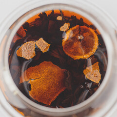 brewed pu-erh in tangerine in a glass teapot top view