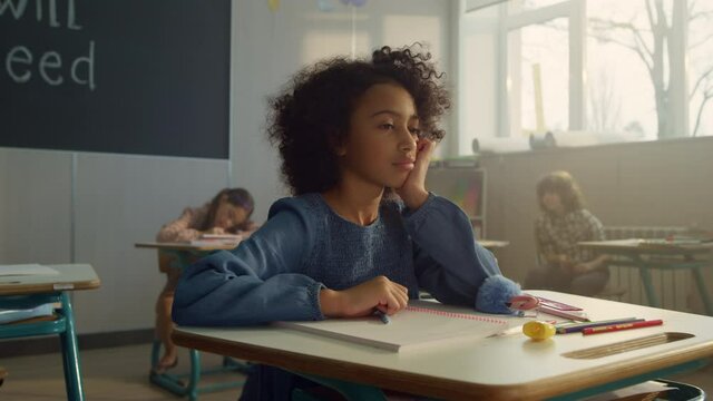 Pensive student sitting at school desk in class. Female pupil learning science
