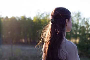 young woman walking away from camera outdoors in sunset with copy space