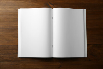 Fototapeta premium Open blank paper brochure on wooden table, top view. Mockup for design