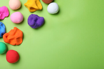 Colorful plasticine on green background, flat lay. Space for text