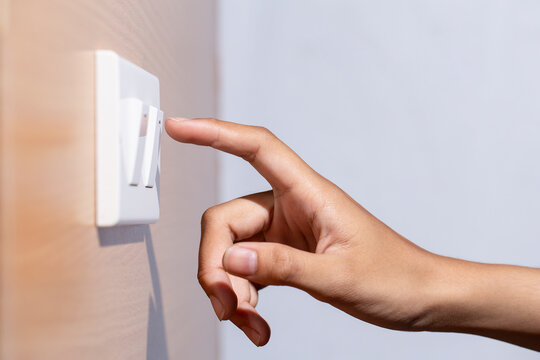 Woman hand is turning on or off electric switch