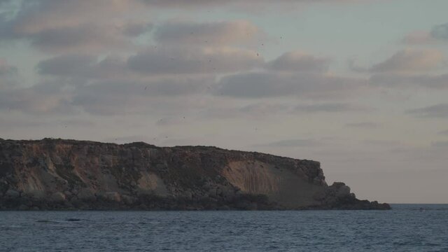 Rocky shore of Agios Georgios Cyprus. View of the island Yeronisos. Sunset at Agios Georgios Pegeias harbor in Paphos, Cyprus. The Akamas peninsula and the island of Geronisos