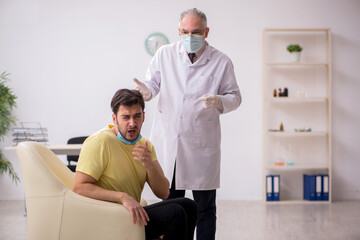 Obraz premium Young male patient visiting old male doctor otorhinolaryngologis