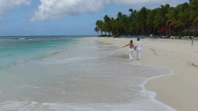 Tropical beach, two people are walking, happy couple in love, aerial footage