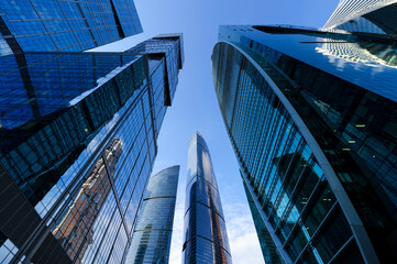 Modern business office skyscrapers, looking up at high-rise buildings in commercial district, architecture raising to the blue sky with white clouds, bottom view 