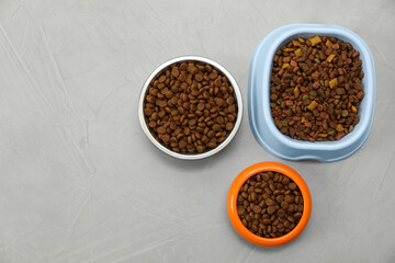 Obraz na płótnie Canvas Dry food in pet bowls on grey background, flat lay. Space for text