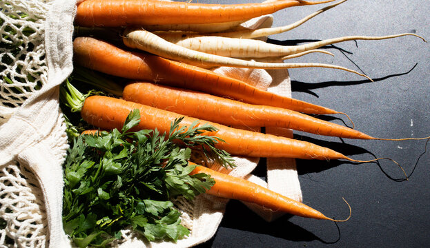 bunch of fresh carrots and parsley in an eco bag. Zero waste, plastic free concept. Sustainable lifestyle. Reusable cotton and mesh eco bags for shopping