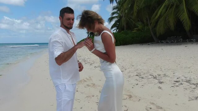 Happy couple putting rings on each other, marriage proposal, tropical beach