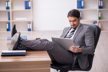 Young attractive male employee sitting at workplace