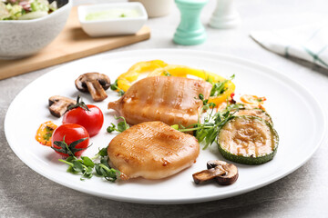 Delicious grilled squid tubes served on grey table, closeup