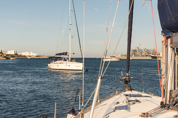 Fototapeta premium The bow of the yacht on the background of the exit from the bay. Focus on the twisted staysail and the yachts are out of focus.