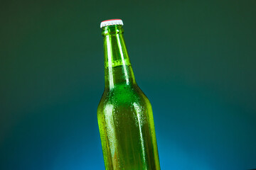 green beer bottle with drops on blue background