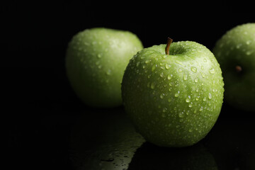 Green apples with water drops on black background, closeup
