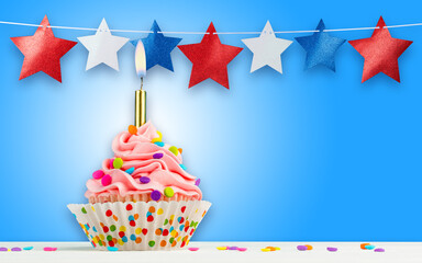 Cupcake and Stars. Happy Birthday, 4th of July, Independence, Memorial or Presidents Day. Tasty cupcakes with pink cream icing and colored sprinkles. Burning candle in a cake. Sweet delicious dessert.