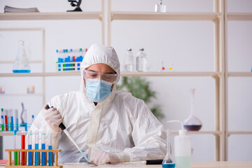 Young male chemist working at the lab during pandemic