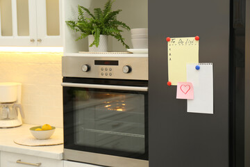 Blank To do list, sticky note and paper on fridge in kitchen. Space for text