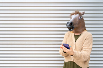 Young horse mask woman using smartphone