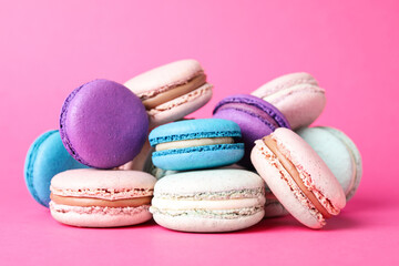 Pile of delicious colorful macarons on pink background