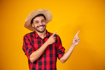 Brazilian man wearing typical clothes for the Festa Junina, Pointing to upper right corner - obrazy, fototapety, plakaty