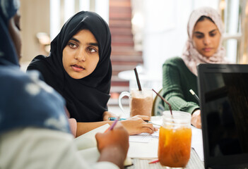 Group of Muslim school girls studying at a cafe together - obrazy, fototapety, plakaty