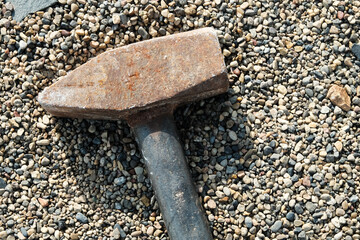 Close-up of large sledgehammer for crushing lies on small pebbles
