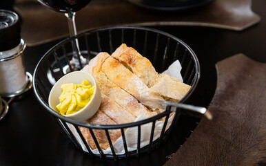 Slices of home baked white bread and small bowl with fresh farmer butter served in metal basket