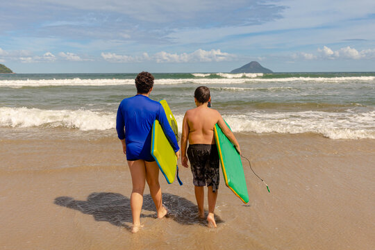 boys going to the sea holding their bodyboard