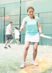 Obraz premium Emotional young adult woman training padel at warm sunny day