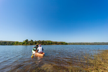 2 men rowing in a river with clear water