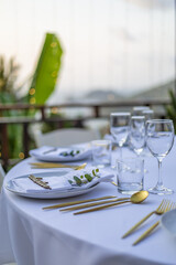 Romantic Wedding Table Top Layout Table Spread no people tropical location with gold cutlery white table cloth and scenic view of sunset with copy space tablescape, beautiful paradise setting