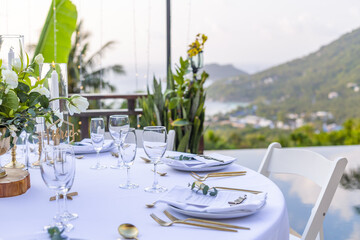 Romantic Wedding Table Top Layout Table Spread no people tropical location with gold cutlery white table cloth and scenic view of sunset with copy space tablescape, beautiful paradise setting