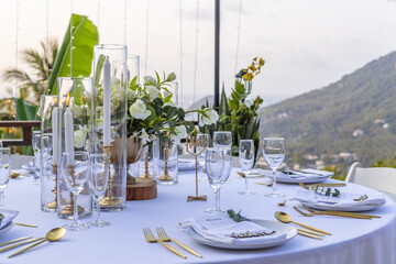 Romantic Wedding Table Top Layout Table Spread no people tropical location with gold cutlery white table cloth and scenic view of sunset with copy space tablescape, beautiful paradise setting