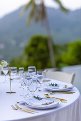 Romantic Wedding Table Top Layout Table Spread no people tropical location with gold cutlery white table cloth and scenic view of sunset with copy space tablescape, beautiful paradise setting