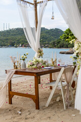 Fototapeta na wymiar Romantic Wedding Table Top Layout Table Spread no people tropical location with gold cutlery and scenic view of sunset on the beach