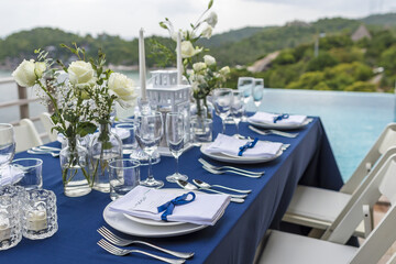 Blue and Silver Romantic Wedding Table Top Layout Table Spread no people catering, event, decor in a tropical location with the sea and clouds in the background